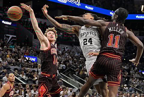 San Antonio Spurs guard Devin Vassell (24) tangles with Chicago Bulls players Leonard Miller (11) and Matas Buzelis  (14) during the first half of an NBA basketball game, in San Antonio.