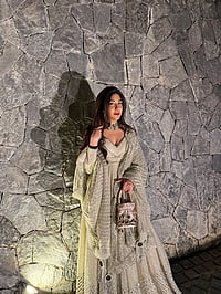 Harmann in a beige lehenga by a rustic stone wall