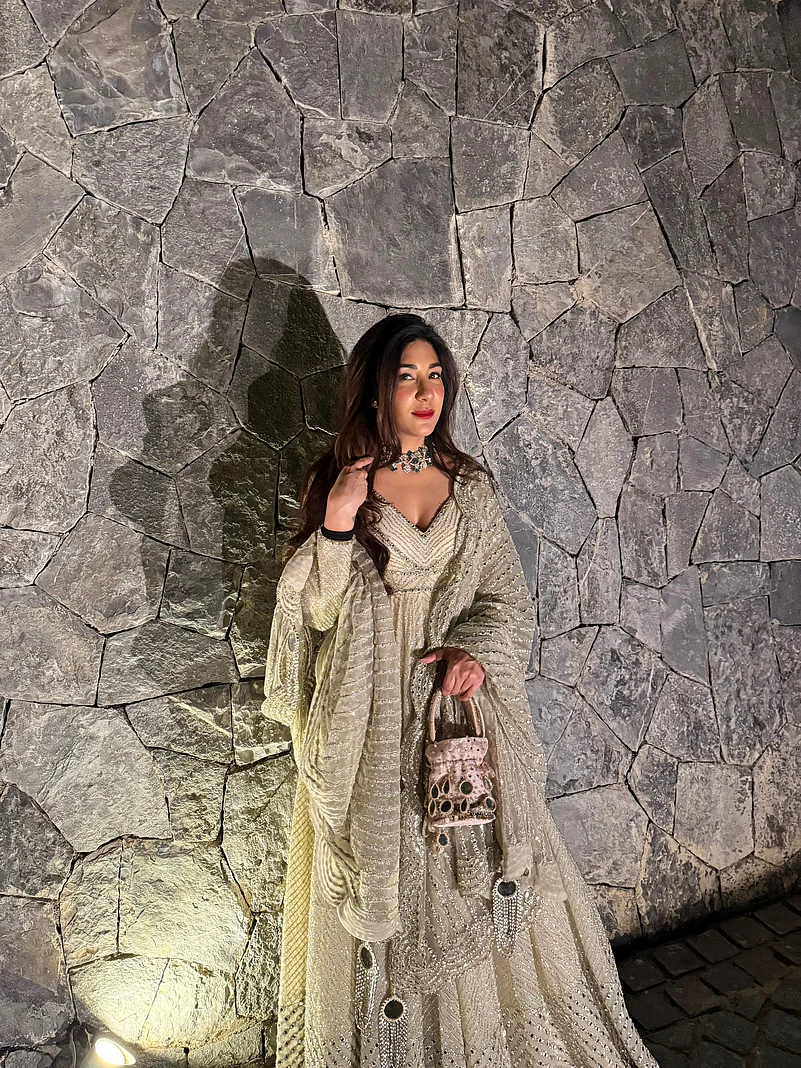Harmann in a beige lehenga by a rustic stone wall