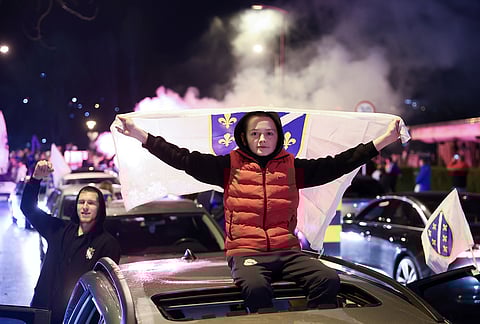 Bosnian fans wave flags as they celebrate after the Bosnian national team qualified for the World Cup by winning a penalty shootout against Italy, in Zenica, Bosnia.