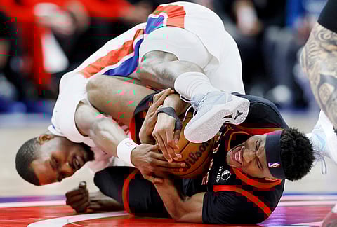 Toronto Raptors guard Ja'kobe Walter, right, and Detroit Pistons guard Javonte Green fight over a loose ball during the first half of an NBA basketball game in Detroit.