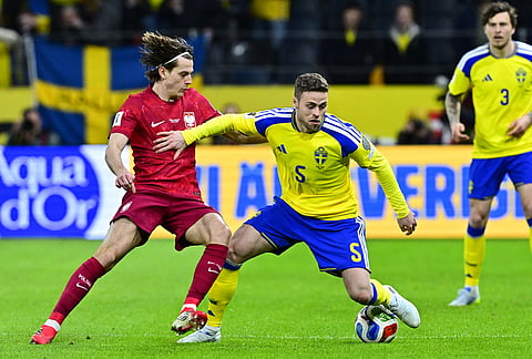 Poland's Jakub Kamiński, left, and Sweden's Gabriel Gudmundsson battle for the ball during a World Cup qualifying playoff final soccer match between Sweden and Poland in Stockholm.