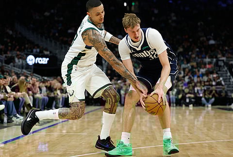 Milwaukee Bucks forward Kyle Kuzma (18) and Dallas Mavericks forward Cooper Flagg (32) reach for the ball during the first half of an NBA basketball game in Milwaukee. 
