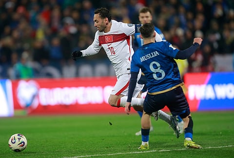 Turkey's Hakan Calhanoglu, left, and Kosovo's Florent Muslija challenge for the ball during the World Cup qualifying playoff final soccer match between Kosovo and Turkey in Pristina, Kosovo.