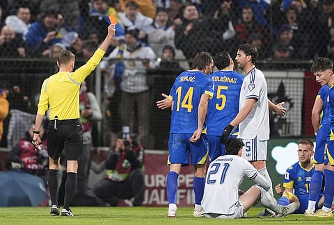 Referee Clement Turpin shows a red card to Italy's Alessandro Bastoni (21) during the World Cup qualifying playoff final soccer match between Bosnia and Italy in Zenica, Bosnia.