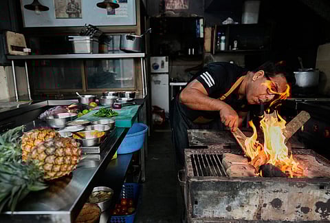 Atul Lahkar, from the Assam region, chef lights a fire with wood and coal to prepare food for his restaurant following a regional gas shortage in Guwahati, Thursday, March 19, 2026. 