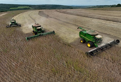 Workers in combines harvest soybeans in Sao Pedro do Turvo, Sao Paulo state, Brazil.