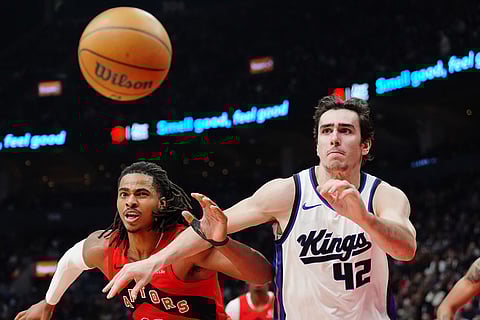 Toronto Raptors' Collin Murray-Boyles (12) and Sacramento Kings' Maxime Raynaud (42) chase down a loose ball during first half NBA basketball action in Toronto.