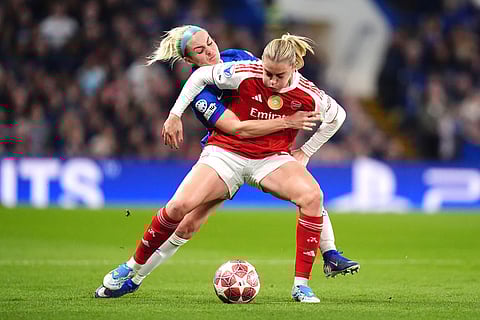 Arsenal's Alessia Russo, left, and Chelsea's Ellie Carpenter battle for the ball during the Women's Champions League quarterfinal second leg soccer match between Chelsea and Arsenal in London.