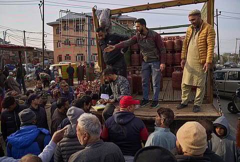 People wait to collect household cylinders of liquefied natural gas from an authorized dealer on a roadside in Srinagar Saturday, March 14, 2026. 