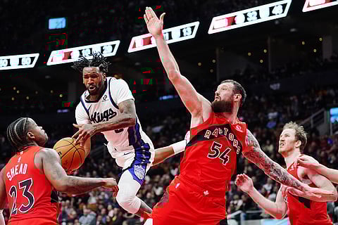 Sacramento Kings' Malik Monk (second left) is fouled as Toronto Raptors' Jamal Shead (23), Sandro Mamukelashvili (54) and Jakob Poeltl (19) defend during second half NBA basketball game in Toronto.