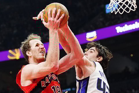 Toronto Raptors' Jakob Poeltl (left) is fouled by Sacramento Kings' Maxime Raynaud (42) during the first half of an NBA basketball game in Toronto.