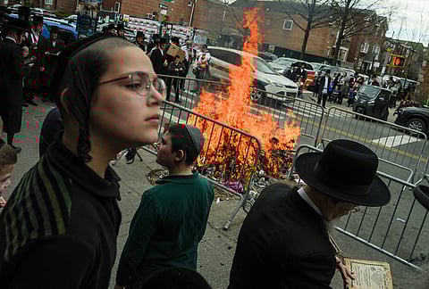 People stand near a fire during "biur chametz," a Jewish ritual where leavened food items are burned on the morning ahead of Passover in New York. 