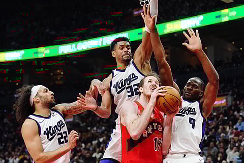 Toronto Raptors' Jakob Poeltl (19) protects the ball from Sacramento Kings' Devin Carter (22), Dylan Cardwell (32) and Precious Achiuwa (9) during the first half of an NBA basketball game in Toronto.