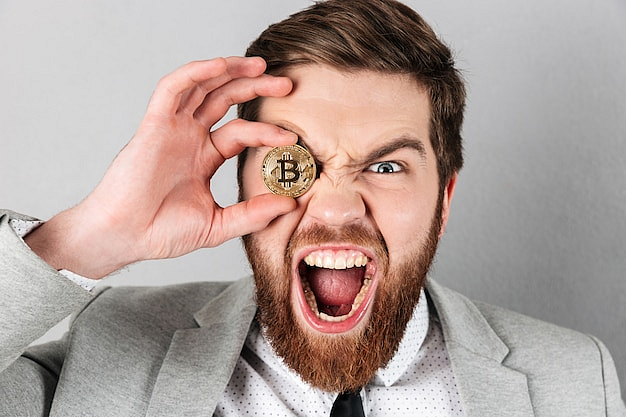 Man holding a Bitcoin coin over one eye and shouting excitedly