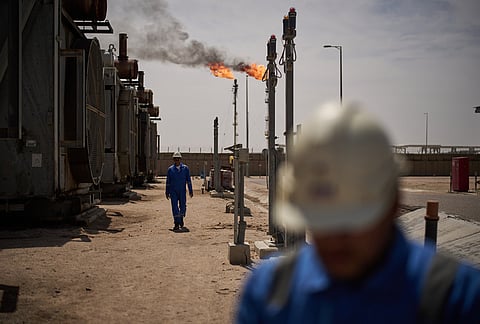 Workers walk in an area at a degassing station in Zubair oil field, whose operations have being reduced due to the Mideast war triggered by the U.S. and Israeli attacks on Iran, near Basra, Iraq, Saturday, March 28, 2026. 