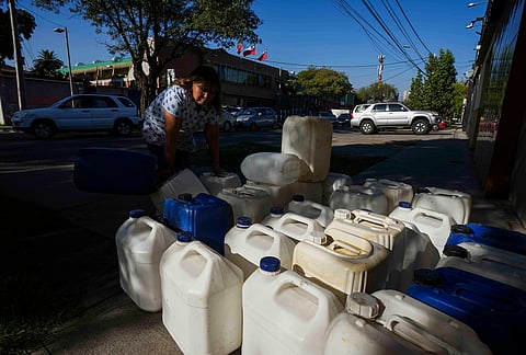 A woman sells portable gas tanks as drivers line up to fill their tanks in Santiago, Chile, Tuesday, March 24, 2026. 