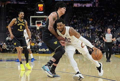 Cleveland Cavaliers guard Donovan Mitchell, right, drives to the basket against Golden State Warriors forward Gui Santos during the second half of an NBA basketball game in San Francisco.