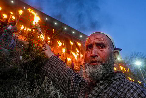 A devotee raises a lit flambeau during the old torch festival in Kashmir, known as Zool or Frow, on Aishmuqam hills, near the Shrine of Hazrat Zain-ud-Din Wali, in Anantnag.
