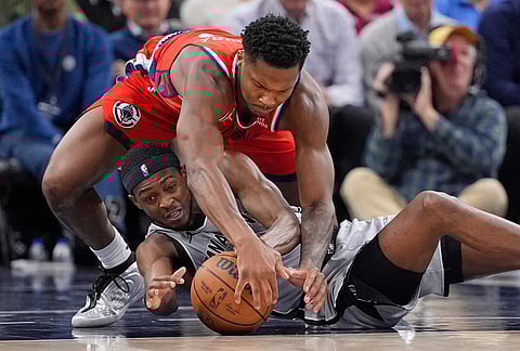 Los Angeles Clippers guard Bennedict Mathurin, top, and San Antonio Spurs guard De'aaron Fox scramble for a loose ball during the second half of an NBA basketball game in Inglewood, California.