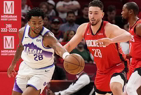 Utah Jazz forward Brice Sensabaugh, left, and Houston Rockets center Alperen Sengun, front right, reach for the ball during the first half of an NBA basketball game, in Houston. 