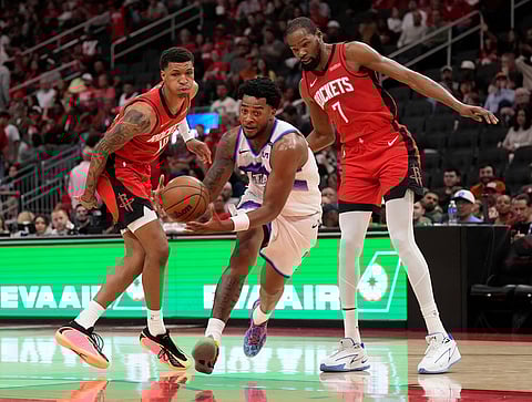 Utah Jazz forward Brice Sensabaugh, center, takes the ball between Houston Rockets forwards Jabari Smith Jr., left, and Kevin Durant (7) during the second half of an NBA basketball game, in Houston.