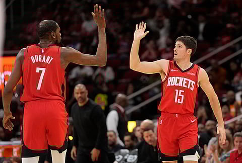 Houston Rockets' Kevin Durant (7) high-fives Reed Sheppard (15) after Sheppard's 3-point basket during the first half of an NBA basketball game against the Utah Jazz, in Houston.