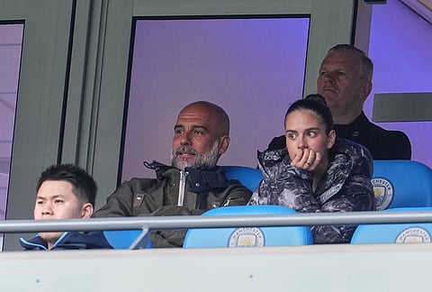 Manchester City's head coach Pep Guardiola watchs from the stand during the FA Cup quarter-final soccer match between Manchester City and Liverpool in Manchester, England.