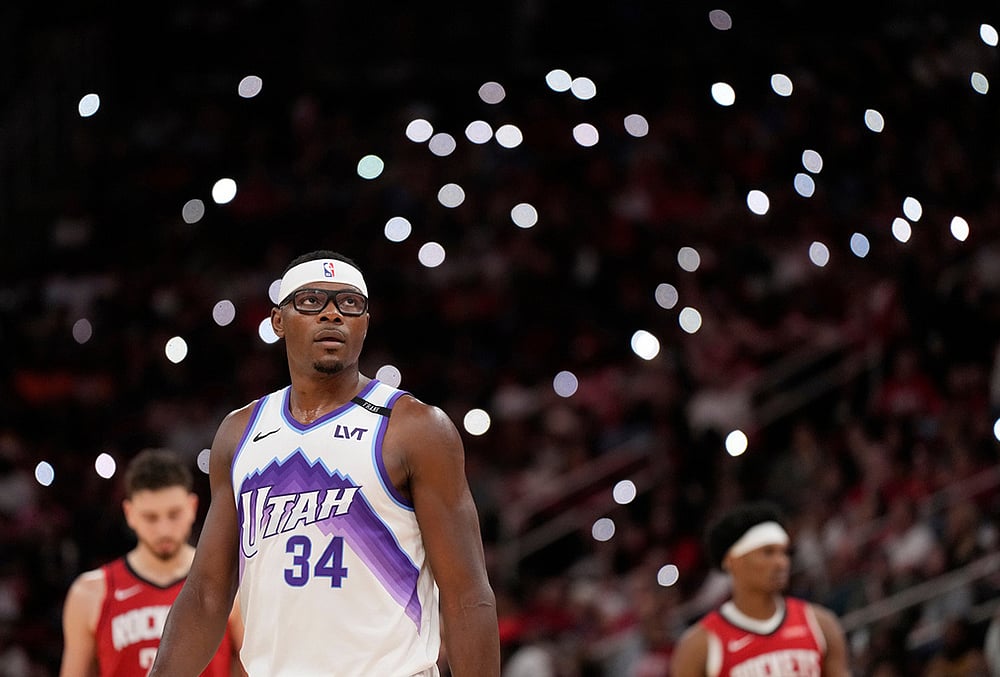 Utah Jazz center Oscar Tshiebwe (34) walks on the court with fans holding up their cell phone flashlights during a timeout during the second half of an NBA basketball game against the Houston Rockets, in Houston. - | Photo: AP/Karen Warren