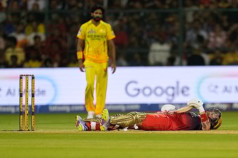 Royal Challengers Bengaluru's Phil Salt lies on the ground after losing balance while playing a shot during the Indian Premier League cricket match between Chennai Super Kings and Royal Challengers Bengaluru in Bengaluru, India.