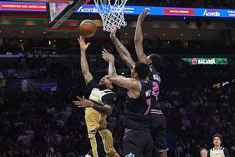 Washington Wizards forward Justin Champagnie (9) aims to score as Miami Heat forward Andrew Wiggins (22) and center Kel'el Ware (7) defend during the first half of an NBA basketball game in Miami.