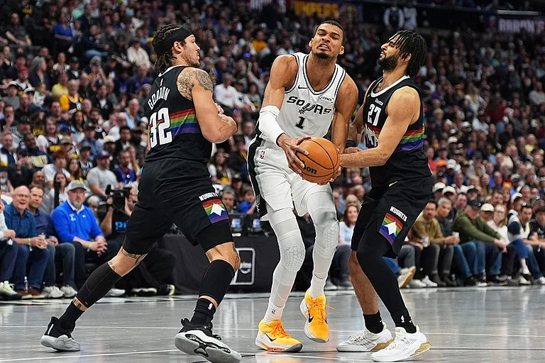 San Antonio Spurs center Victor Wembanyama is fouled by Denver Nuggets guard Jamal Murray, right, while driving past forward Aaron Gordon in the first half of an NBA basketball game in Denver. - | Photo: AP/David Zalubowski