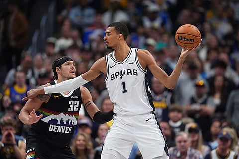 San Antonio Spurs center Victor Wembanyama, right, looks to pass the ball as Denver Nuggets forward Aaron Gordon defends during overtime of an NBA basketball game in Denver.
