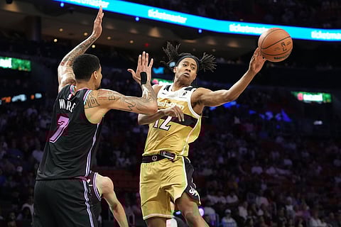 Washington Wizards guard Tre Johnson (12) passes the ball under pressure from Miami Heat center Kel'el Ware (7) during the first half of an NBA basketball game in Miami.