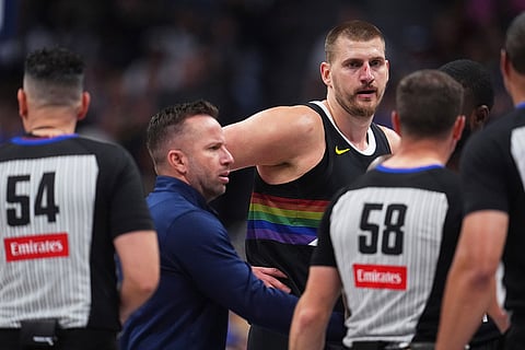 Denver Nuggets center Nikola Jokić, back right, argues for a call after being hit in the nose as assistant coach J.J. Barea, back left, intercedes with referees Ray Acosta, front left, and Josh Tiven in the first half of an NBA basketball game against the San Antonio Spurs in Denver.