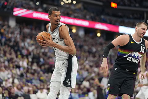 San Antonio Spurs center Victor Wembanyama, pulls in a rebound next to Denver Nuggets center Nikola Jokic in the second half of an NBA basketball game in Denver.