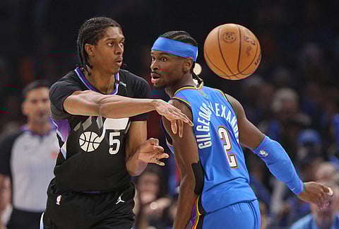 Utah Jazz forward Cody Williams (5) passes the ball away from Oklahoma City Thunder guard Shai Gilgeous-Alexander (2) during the first half of an NBA basketball game in Oklahoma City.