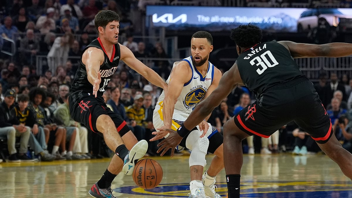Houston Rockets guard Reed Sheppard, left, kicks a pass by Golden State Warriors guard Stephen Curry, center, during the first half of an NBA basketball game, Sunday, April 5, 2026, in San Francisco.  - (AP Photo/Godofredo A. Vásquez)