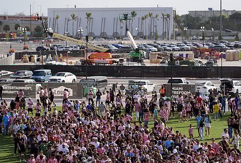 Fans wait in line to enter Nu Stadium, as signs of ongoing work are seen behind, ahead of the team's first MLS soccer match in their new stadium, against Austin FC in Miami. 