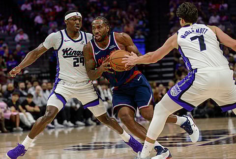 Los Angeles Clippers forward Kawhi Leonard, center, drives past Sacramento Kings guard Daeqwon Plowden (29) and forward Doug McDermott (7) during the second half of an NBA basketball game in Sacramento, California.