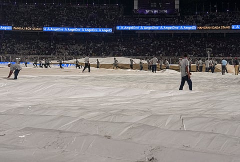 Ground staff cover the ground during rain interruption in an Indian Premier League (IPL) 2026 cricket match between Kolkata Knight Riders and Punjab Kings at Eden Gardens, in Kolkata.