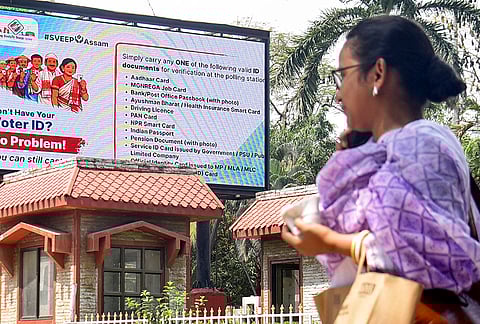 A woman passes by a digital display raising awareness regarding voting ahead of the Assam Assembly Election, at the state Secretariat, in Guwahati.