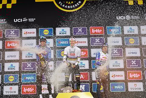 Slovenia's Tadej Pogacar celebrates after winning the Tour of Flanders cycling race, with Netherland's Mathieu Van Der Poel, left, finishing second and Belgium's Remco Evenpoel third in Oudenaarde, Belgium.