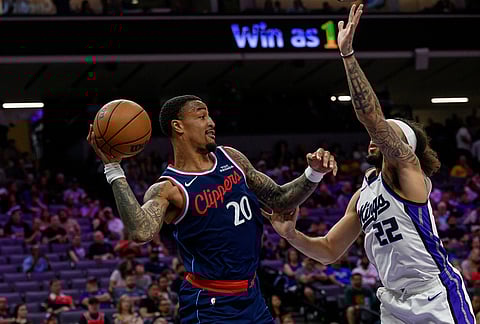 Los Angeles Clippers forward John Collins (20) prepares to pass the ball past Sacramento Kings guard Devin Carter (22) during the second half of an NBA basketball game in Sacramento, California.