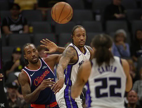 Sacramento Kings guard DeMar DeRozan passes the ball to Sacramento Kings guard Devin Carter (22) past Los Angeles Clippers forward Kawhi Leonard (2) during the first half of an NBA basketball game in Sacramento, California.
