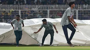 AP : Ground staff pull in covers to the field as it rains during the Indian Premier League match between Kolkata Knight Riders and Punjab Kings in Kolkata.