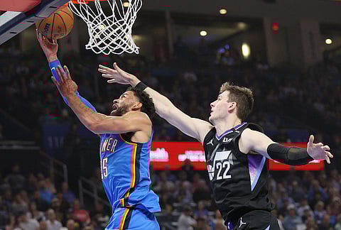 Oklahoma City Thunder guard Ajay Mitchell (25) looks to score past Utah Jazz forward Kyle Filipowski (22) during the first half of an NBA basketball game in Oklahoma City. 