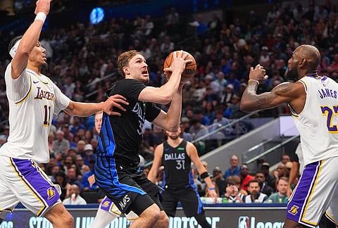 Dallas Mavericks forward Cooper Flagg (32) drives against Los Angeles Lakers defenders LeBron James (23) and Jaxson Hayes (11) during the second half of an NBA basketball game in Dallas.