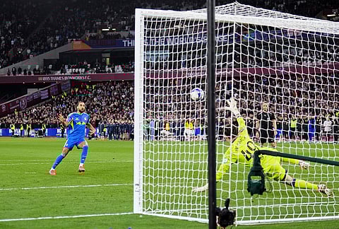 Leeds United's Dominic Calvert-Lewin, left, scores in the penalty shoot-out during the English FA Cup quarterfinal soccer match between West Ham United and Leeds United, in London.