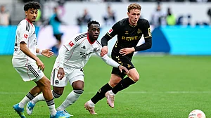 | Photo: dpa/Uwe Anspach via AP : Cologne's Sebastian Sebulonsen, right, and Frankfurt's Nathaniel Brown, left, and Arnaud Kalimuendo battle for the ball during the German Bundesliga soccer match between Eintracht Frankfurt and 1. FC Cologne in Frankfurt, Germany, Sunday, April 5, 2026.